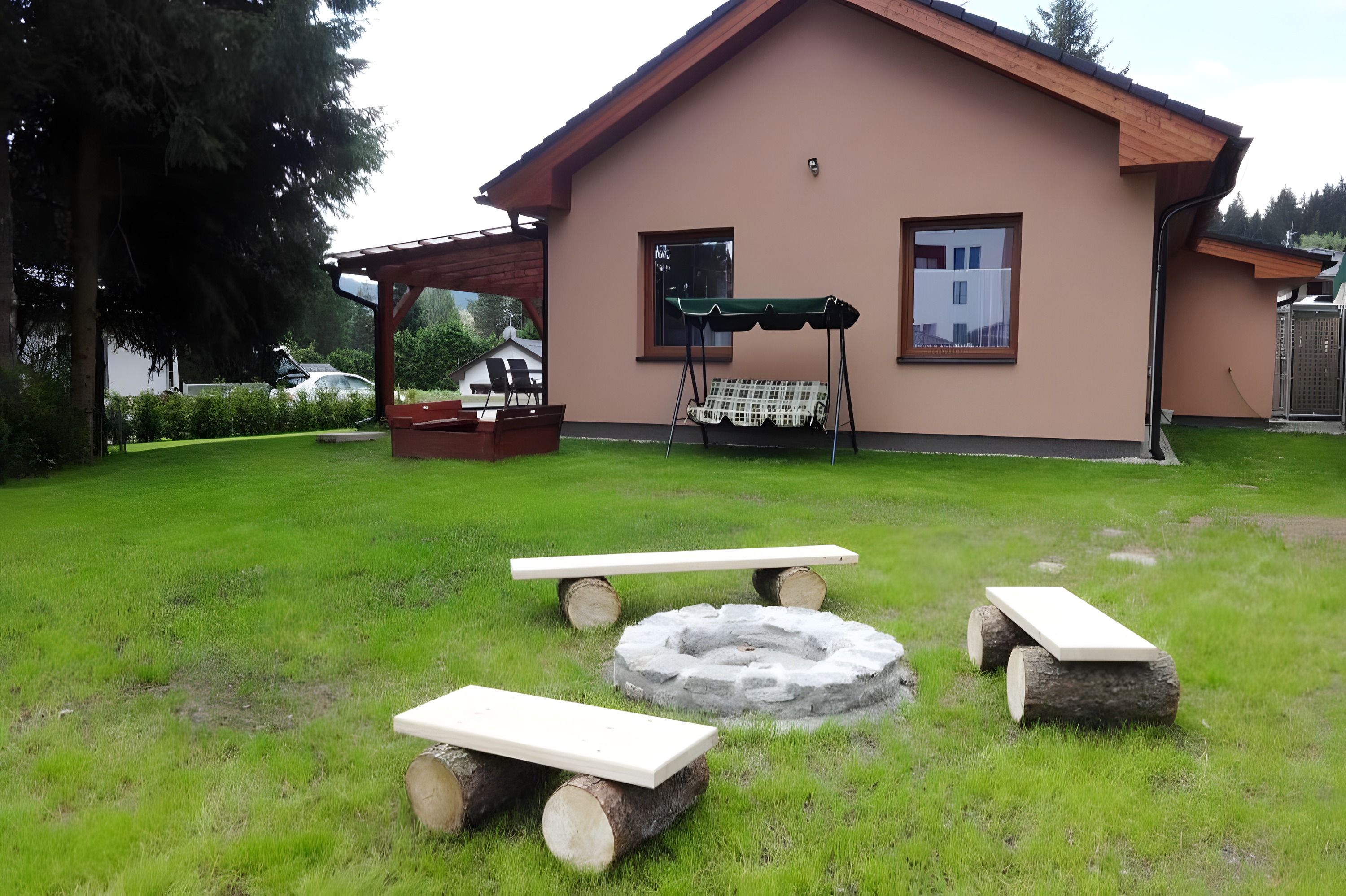 Ohniště s lavičkami na trávníku u chaty